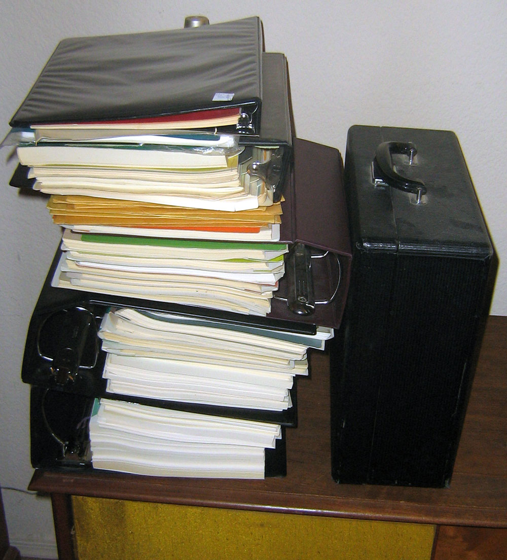 The giant pile of Brother typewriter service manuals, parts lists and factory service updates, finally organized chronologically and put in new binders. Shown next to a typewriter case for size comparison.